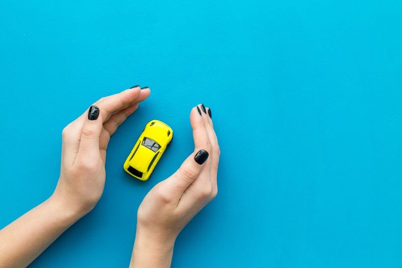 concepto swguro coche manos de mujer encarrando un coche amarillo de juguete